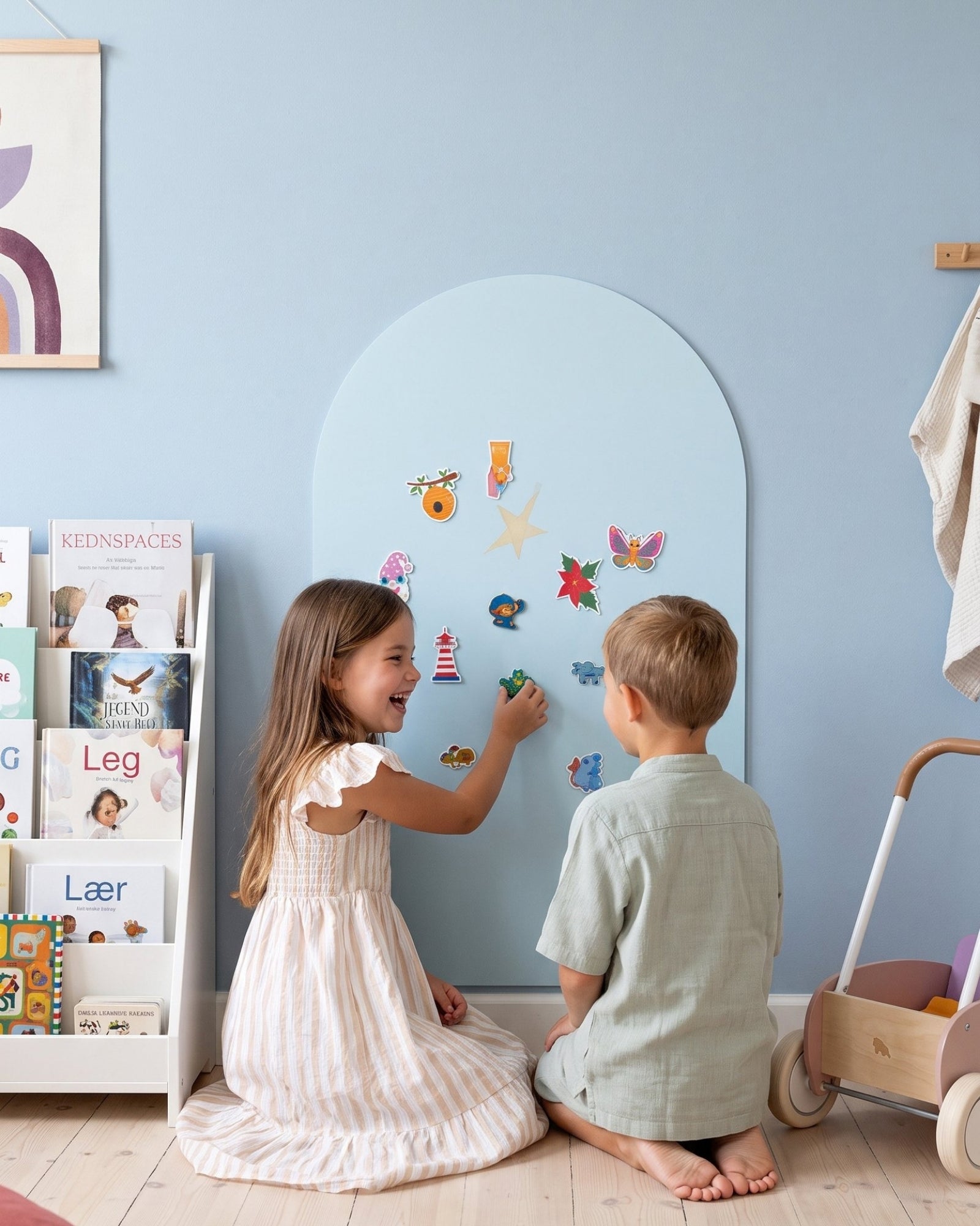 Meisje en jongen spelen met magneten op de MagneetBoog+ in HimmelDyne (lichtblauw) bij boekenplank op kinderkamer